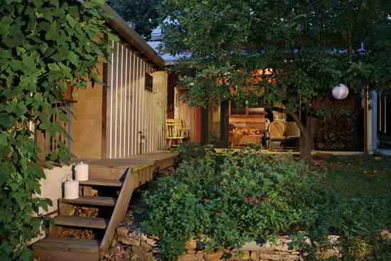 
On the side of the house are two porches. One, to the left, is shielded from view by kudzu and houses a wood-fired pizza oven. The other is shaded by an apple tree. The yard’s flowers and herbs attract bees and hummingbirds.
